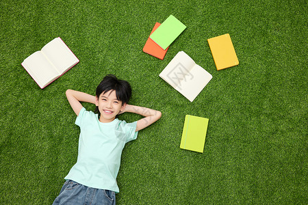 小女孩躺在铺满书本的草地上图片