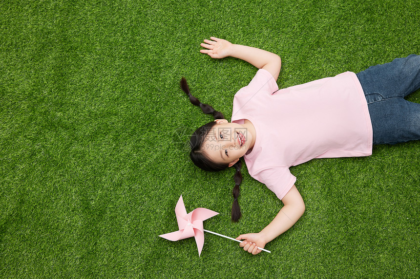 小女孩拿着粉色风车躺在草地上图片