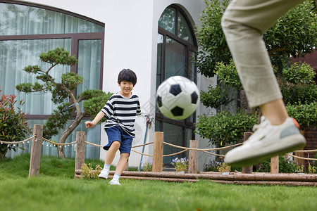 孩子在草地上和父亲踢足球图片