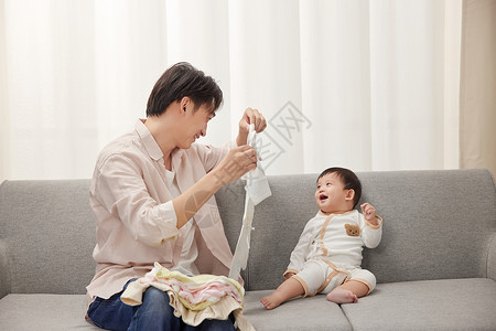 沙发上叠衣服的爸爸和宝宝互动图片