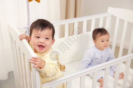 婴儿床上开心玩耍的双胞胎背景图片