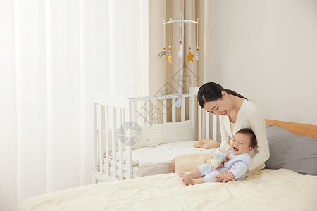 在床上和宝宝玩耍的妈妈背景图片