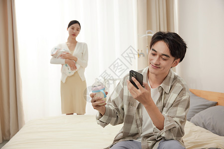 父亲抱孩子抱孩子的母亲和拿着奶瓶玩手机的父亲背景