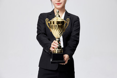 手拿奖杯获奖的商务女性背景图片