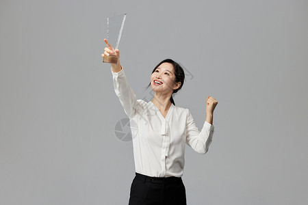高举奖杯的商务女性背景图片