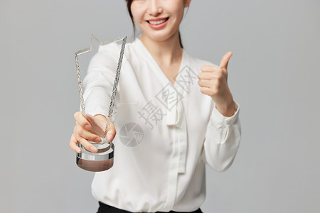 手拿奖杯的商务女性背景图片