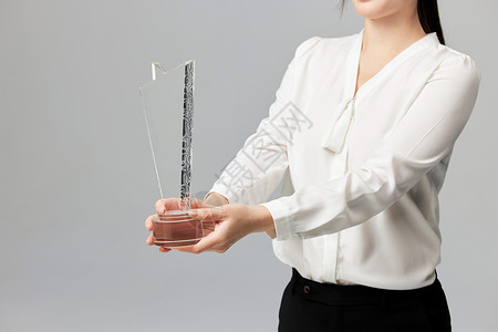 手拿奖杯的商务女性手部特写背景图片