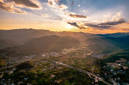 航拍夕阳下的西双版纳植物园建筑和森林背景图片