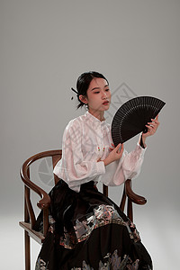 手拿扇子坐在椅子上的新中式马面裙美女高清图片