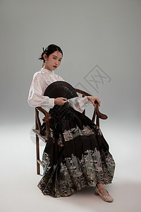 手拿扇子坐在椅子上的新中式马面裙美女高清图片