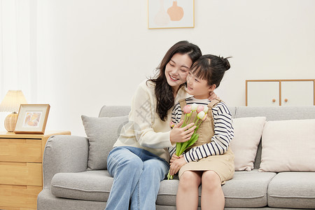 拿着花束女孩母亲在沙发上依偎着女儿背景