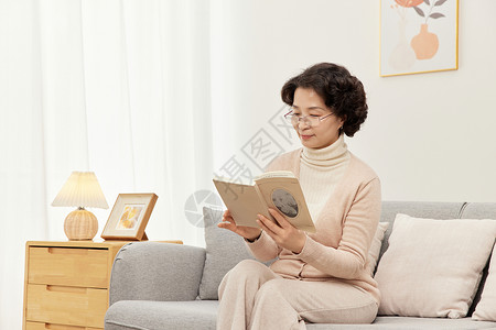 沙发上的手机奶奶在沙发上优雅的看书背景