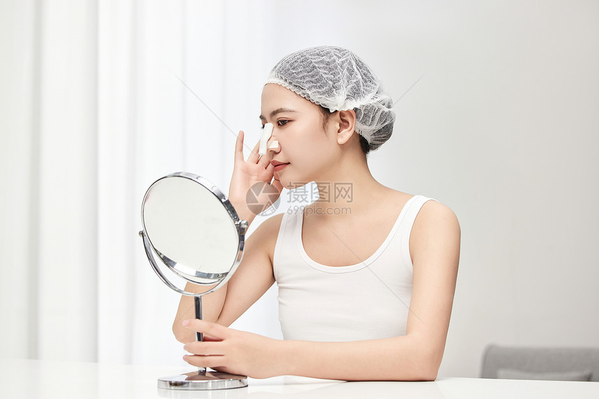戴着鼻夹在镜子面前做搞怪表情的可爱女生图片