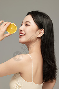 微笑水果举着橙子片拍照的侧颜气质美女背景