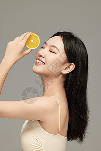 侧颜美女举着橙子片拍照的侧颜气质美女背景