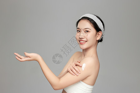 身体乳主图模特微笑向镜头展示手臂上擦的身体乳背景