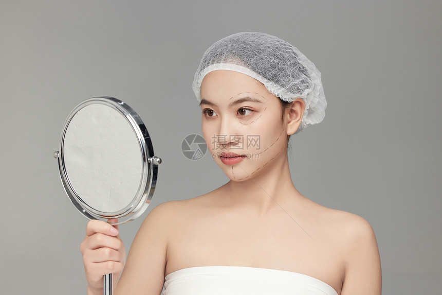 镜子前检测自己皮肤状态的美女图片