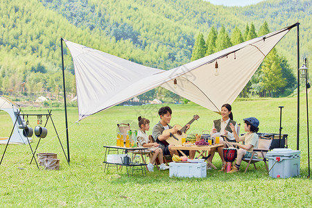 一家人在郊游快乐的一家人在草地上户外露营背景
