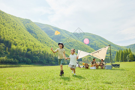 户外露营两个孩子在草坪上抓蝴蝶高清图片