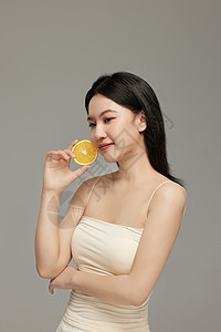 美容摆拍手上拿着橙子片自信展示皮肤状态的气质美女背景