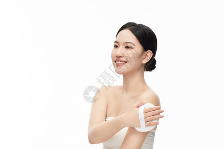 化妆品拍摄背景用大粉扑轻拍手臂的年轻模特形象背景
