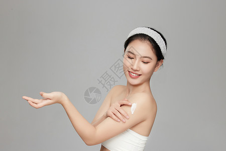 身体乳主图微笑展示手臂上身体乳的年轻女孩背景