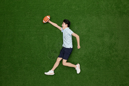 创意俯拍手上拿着橄榄球的热血青年背景图片