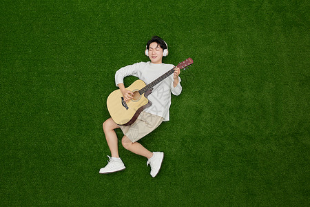 弹吉他男孩坐姿创意俯拍戴着耳机的吉他男孩背景