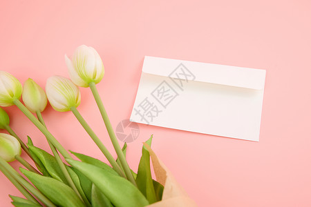 爱老师粉色桌面上的白色信封和郁金香背景