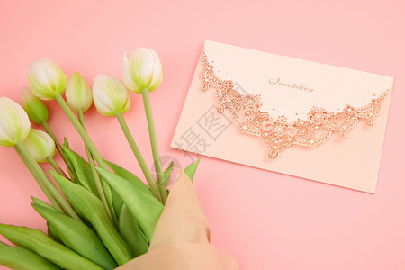 粉色信封桌面上的白色郁金香与华丽白色信封特写背景