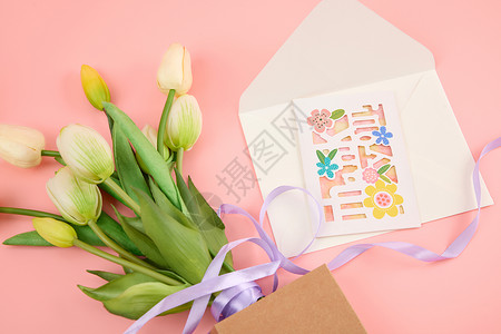 信封打开粉色桌面上一束白色郁金香和一个打开的信封背景