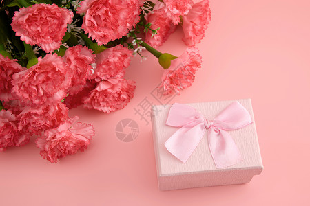 浅红色蝴蝶结一大束娇艳欲滴的红色康乃馨和粉色蝴蝶结礼物盒背景
