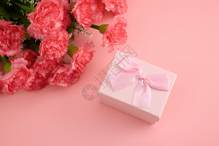 母亲节花束标语一大束娇艳欲滴的红色康乃馨和粉色蝴蝶结礼物盒背景