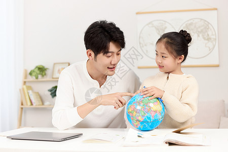 拿着地球仪的爸爸正温柔给女儿讲解地理知识高清图片