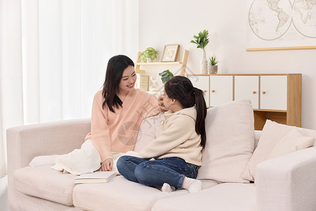 室内温馨沙发上亲昵靠在一起看书的母女俩背景