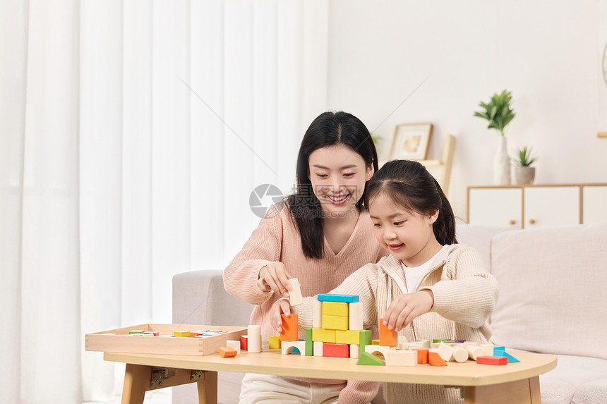 年轻妈妈正和女儿一起堆积木玩耍图片