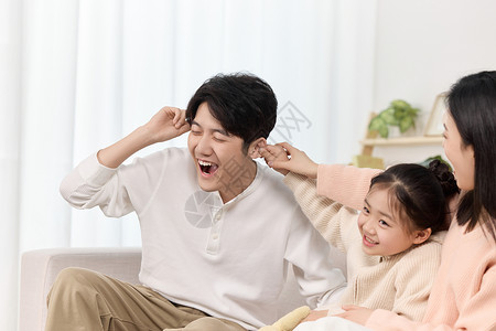 注意搞笑沙发上母女俩正欢快地扯着爸爸的耳朵背景