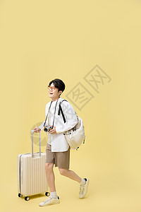 背着书包推着行李箱旅游的年轻大学生背景图片