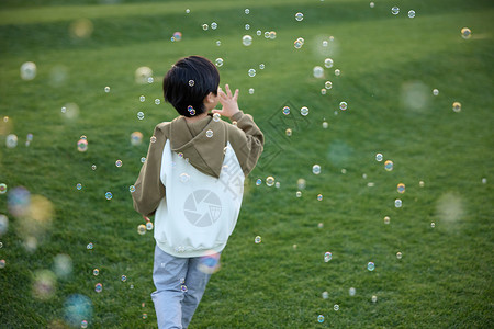 泡泡玩具小男孩在草坪上吹泡泡背景