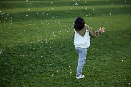 吹泡泡的男孩小男孩在草坪上吹泡泡背景