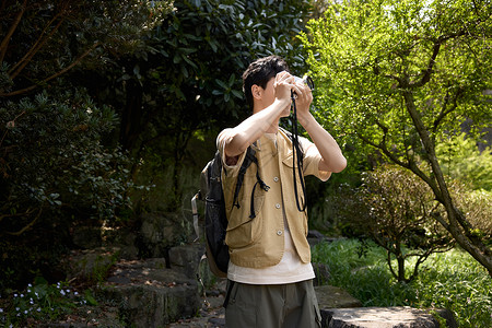 旅游的男人帅气小伙在山上用相机拍山景背景