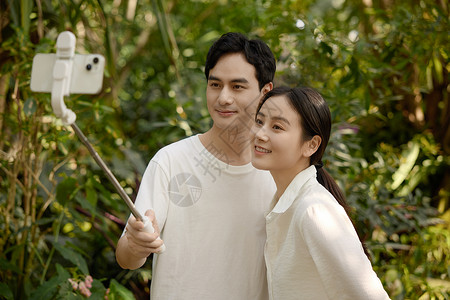 开心合照一对情侣在植物园拿着自拍杆自拍背景