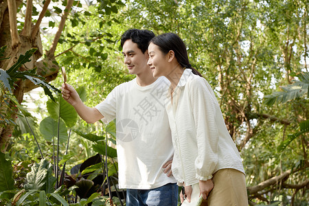 植物园里仔细观察的年轻情侣高清图片