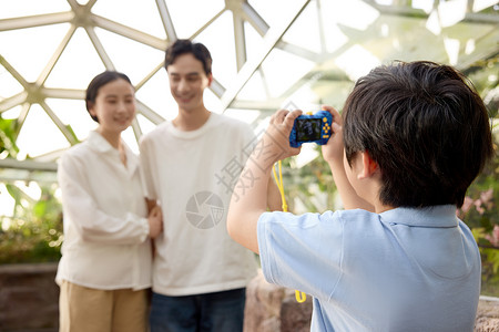 爸爸妈妈合影植物园里正在给爸爸妈妈拍照的小男孩背景