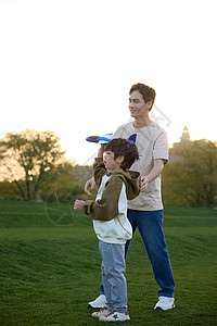 儿童飞机草坪上教儿子玩飞机模型的爸爸背景