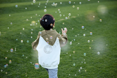 泡泡中男孩在草坪上玩泡泡的小男孩背景