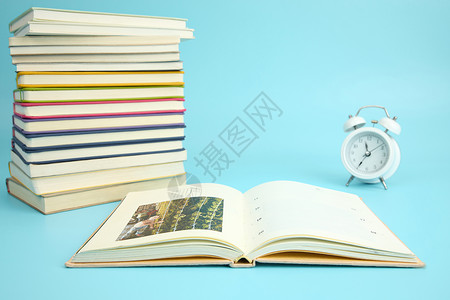 钟表面时钟屏保一叠彩色的书籍边有一本翻开的书与闹钟背景