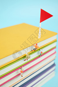 彩色旗帜飘带在一叠彩色书本上攀登的微距小人背景