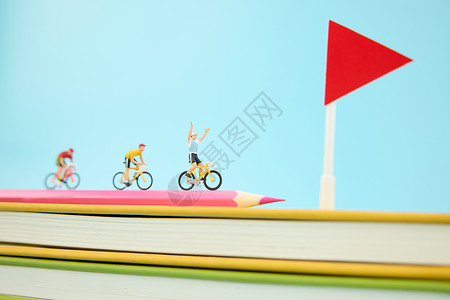 站在书本上在一叠彩色书本上骑行冲向终点的微距小人背景
