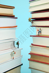 小人读书素材在书本间向上攀登的微距小人背景